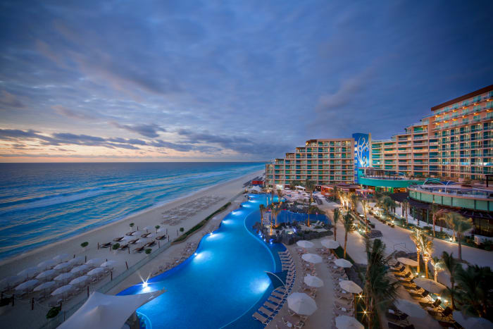 Piscine et plage au crépuscule du Hard Rock Hotel Cancún. 