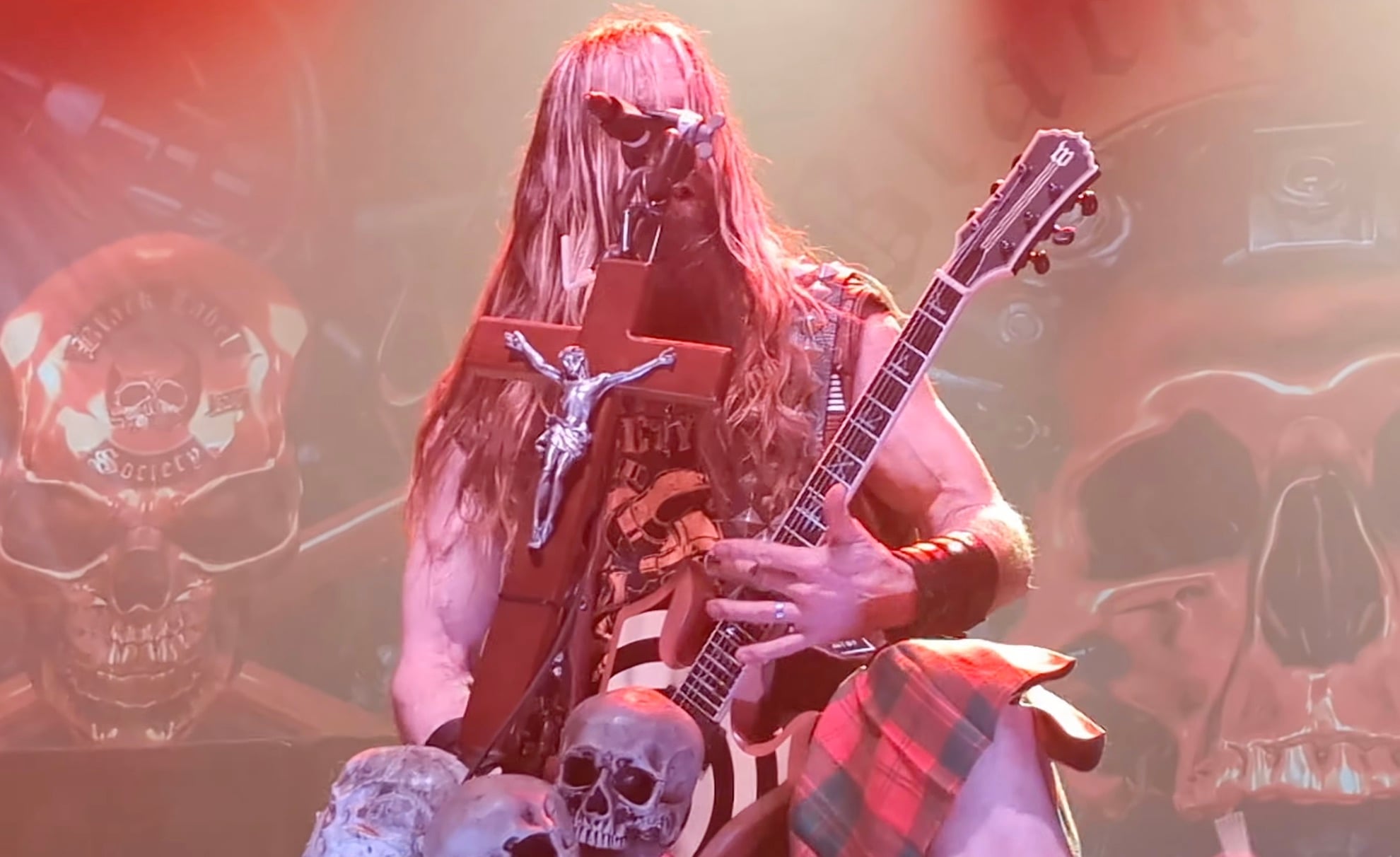 Zakk Wylde playing guitar on stage with Black Label Society during a live concert, with dramatic lighting and audience in the background.
